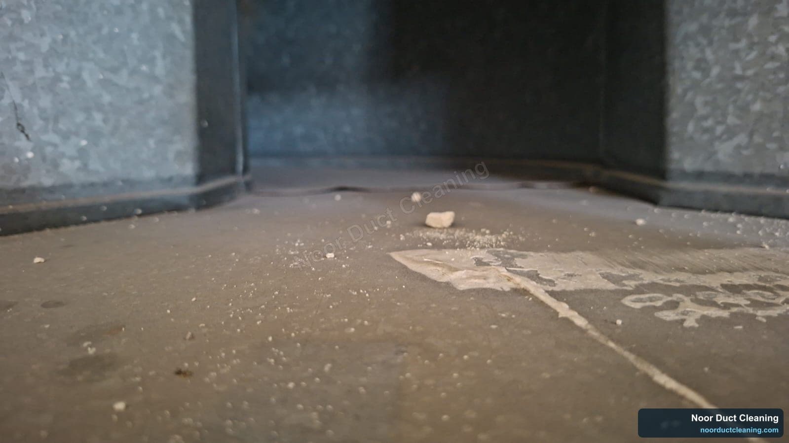 AC duct interior on a Dubai job before and after cleaning, a drift of loose dust and debris along the duct floor removed